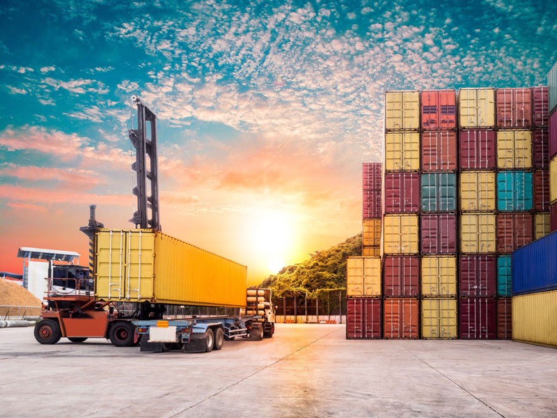 shipping containers stacked in industrial yard waiting to be loaded onto semi trucks